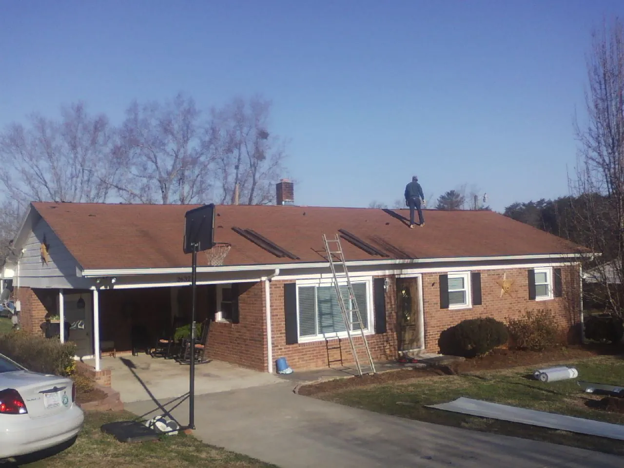 Roofer stripping a shingle roof on a brick ranch before metal panels in Boonville