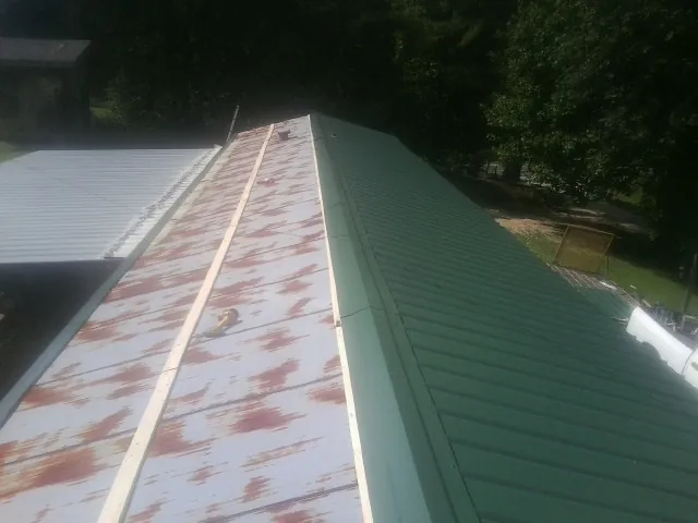 Old rusted panels beside newly installed green metal roofing — Wind Damage Roof Repair by Roofing Brothers in Boonville