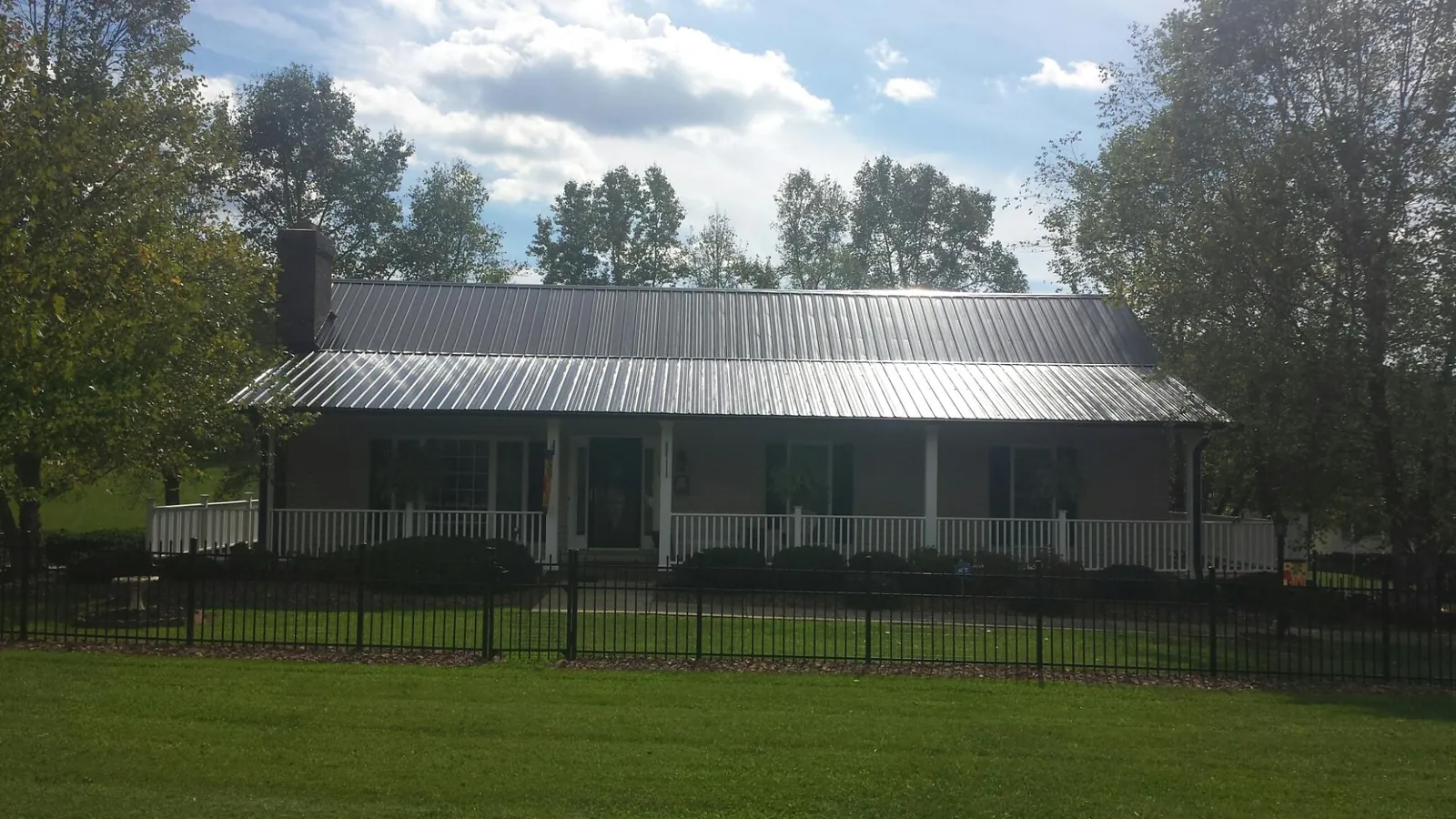 Gray metal roof on a brick ranch with a full width front porch — Gutter Guard Installation work by our crew in Boonville