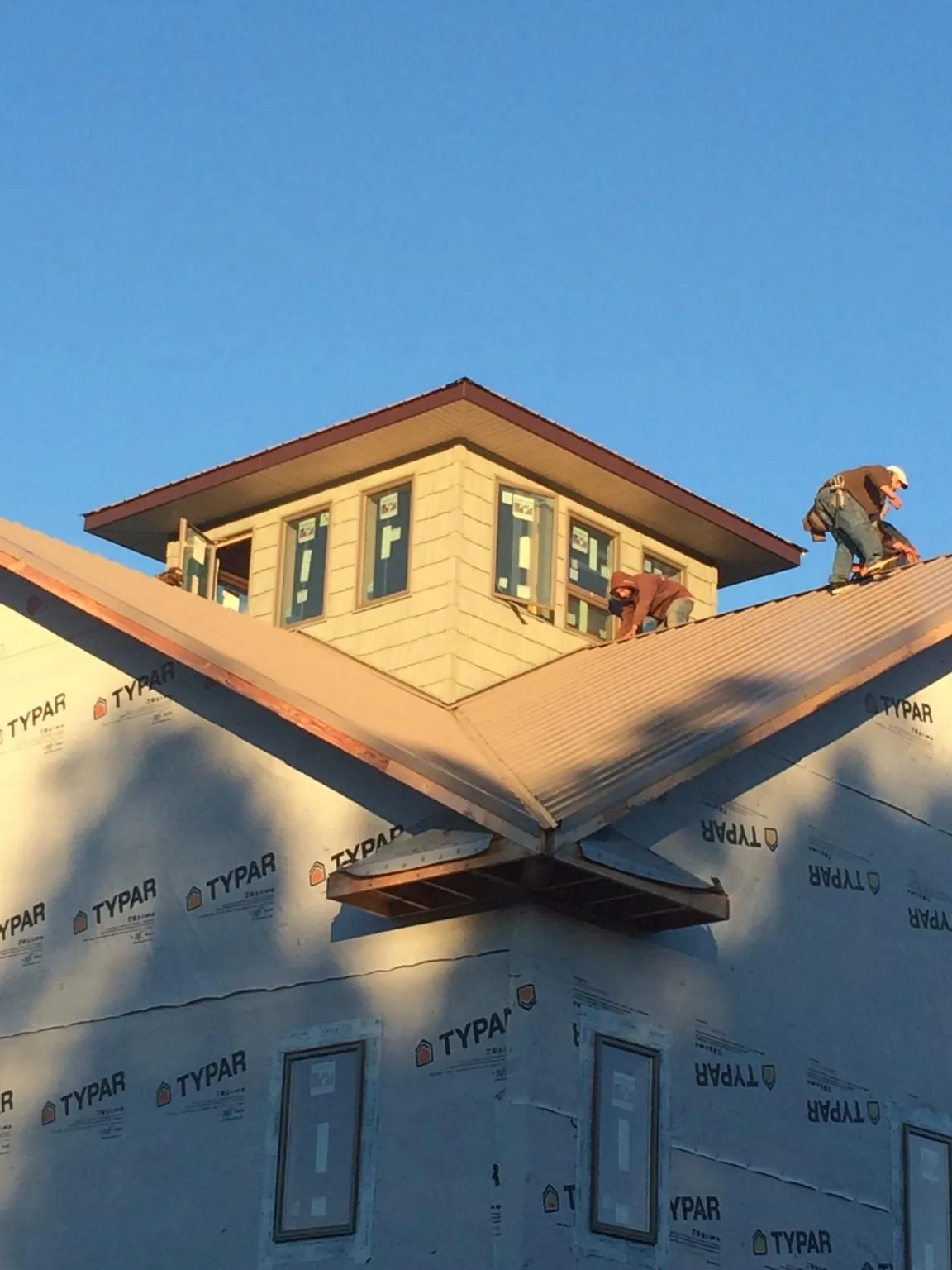 Roofers working around a rooftop cupola on a new metal roof at sunset — Roof Waterproofing in Boonville by Roofing Brothers
